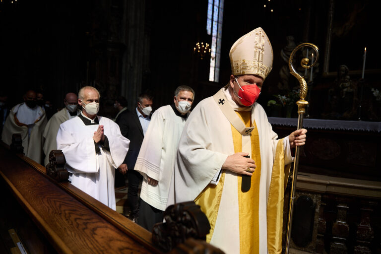 Kardinal Christoph Schönborn in festlichem liturgischen Geand mit Krummstab und roter Atemschutz-Maske im Stephansdom Wien.