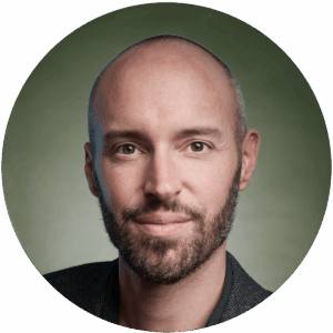 Portrait eines Mannes mit Bart vor grünem Hintergrund, direkter Blick in die Kamera